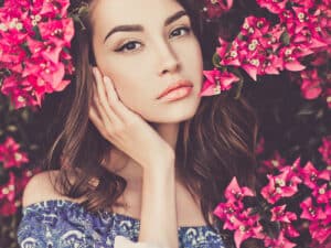 Outdoor fashion photo of beautiful young woman surrounded by flowers