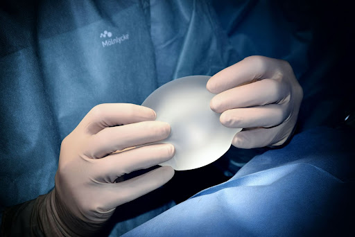 physician in gloves holding gummy bear breast implant
