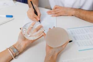 Woman holding two different breast implants for her breast augmentation in Savannah