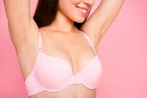 Woman smiling in pink bra showing her mini breast augmentation in Savannah, GA