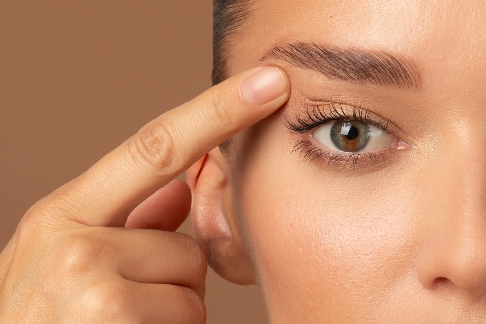 Close up of woman's eye as she points to her eyelid after eyelid surgery in Savannah, GA