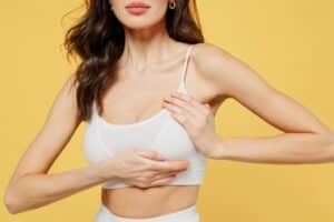 Woman in bra touching her breast after breast implant surgery in Savannah, GA
