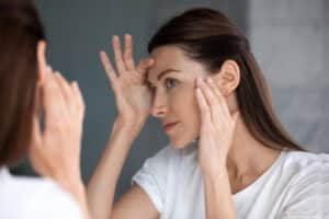 Woman looking in the mirror at her healthy-looking skin after a chemical peel in Savannah, GA